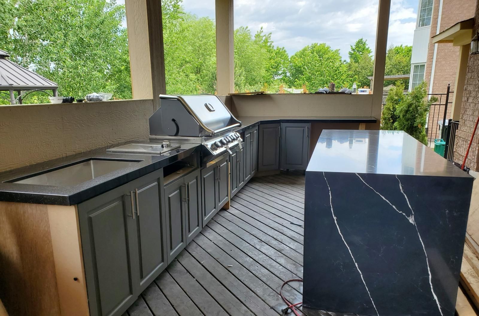 Outdoor kitchen with black stone countertops, built-in BBQ and waterfall island